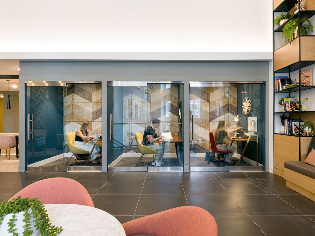 a group of people sitting at tables in a room with glass doors