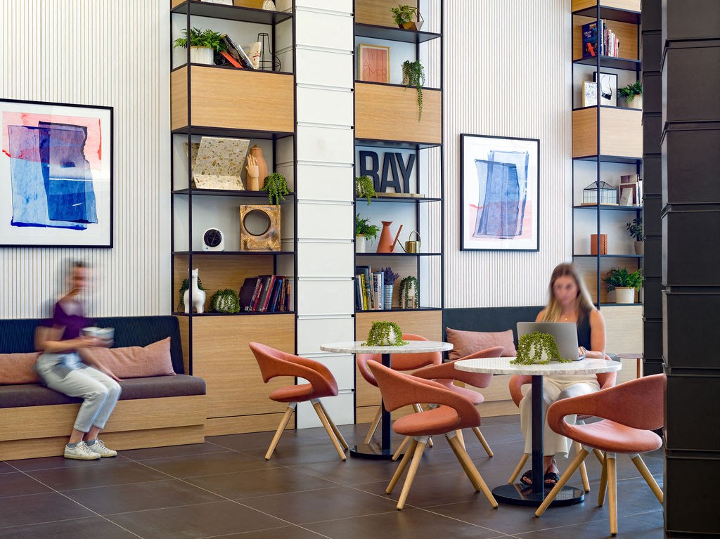 a group of people sitting in a room with tables and chairs