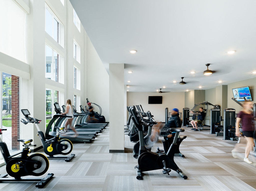 a gym with cardio machines and people on treadmills