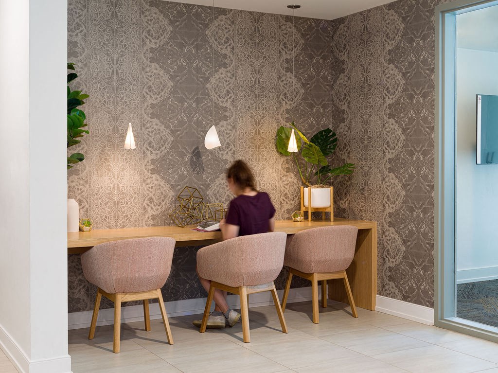 a woman sitting at a desk in a room with chairs