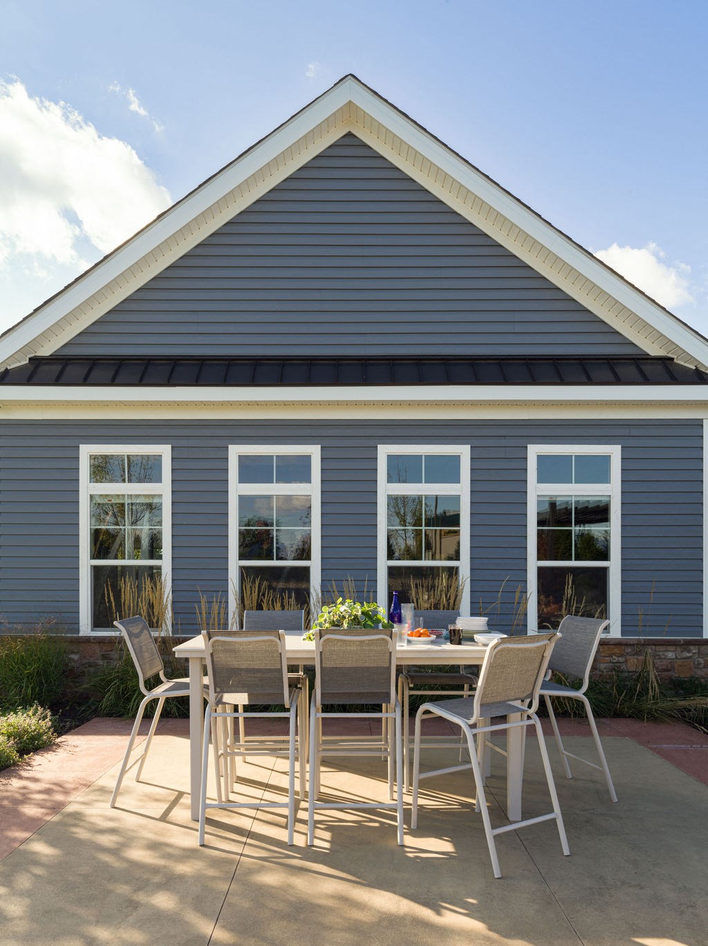 a patio with a table and chairs in front of a blue house