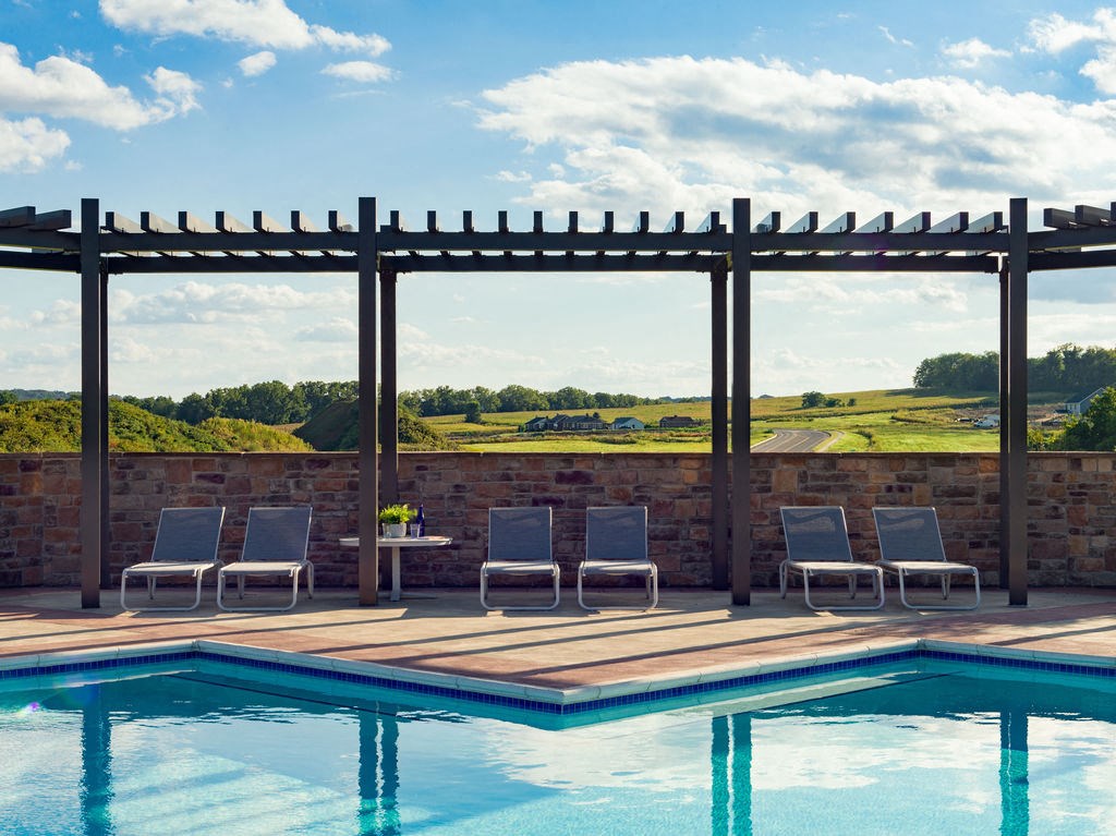 a swimming pool with chairs and a view of a field