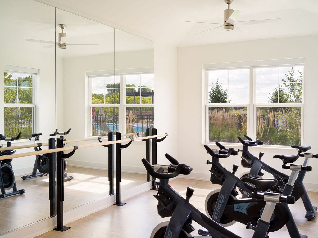 a gym with spin bikes in a room with windows