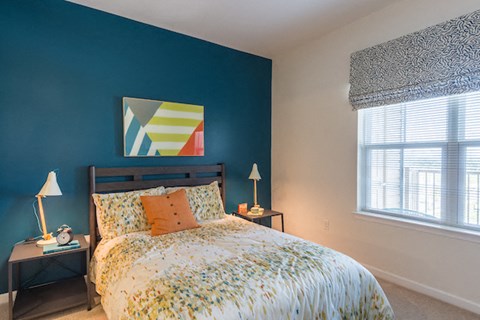 A bedroom with a bed, nightstands, and a window.