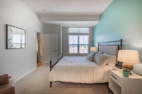 A bedroom with a bed, nightstand, and chair.