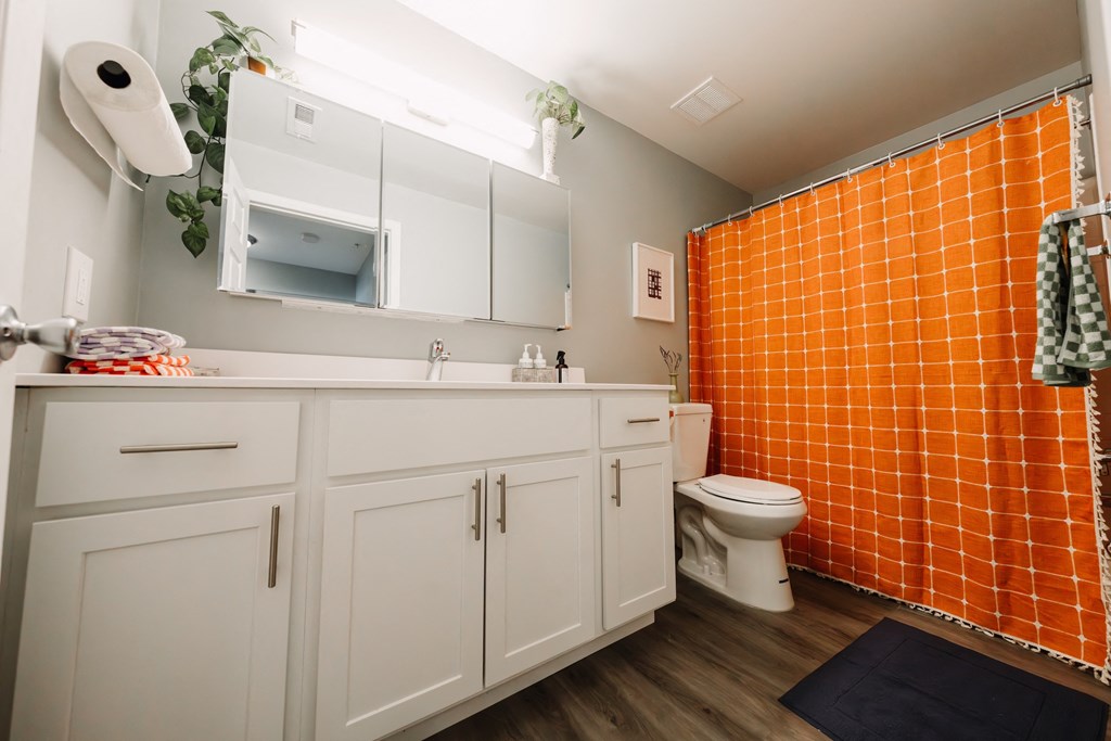 a bathroom with a orange shower curtain and a white sink and toilet