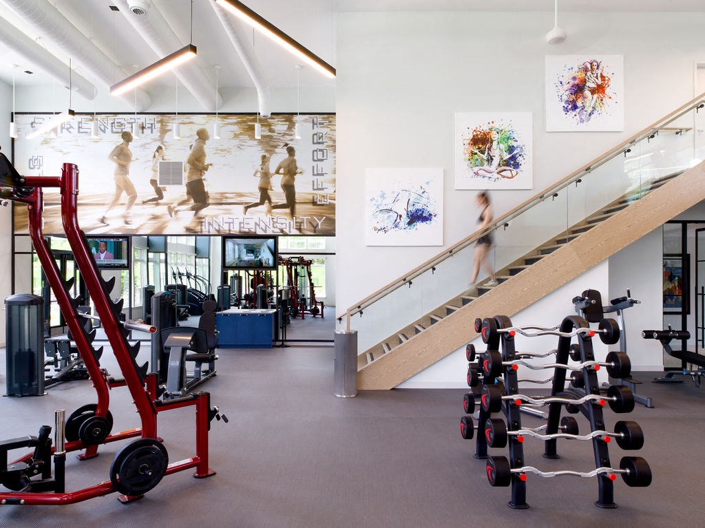 a gym with weights and a staircase and art on the wall