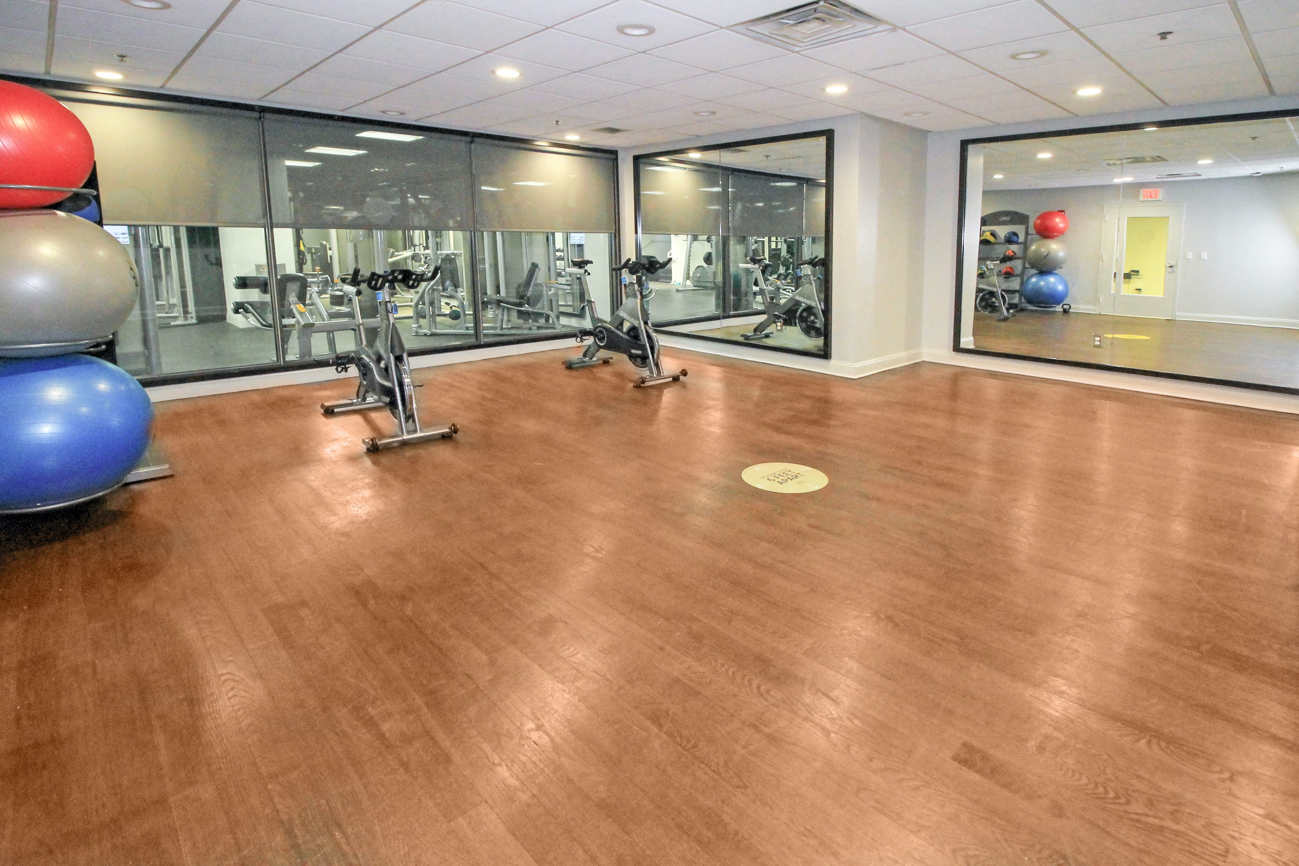 a gym with cardio equipment and mirrors in a room with wood floors