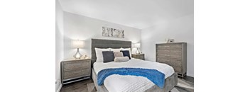 A bedroom with a large bed, two nightstands, and a painting on the wall.