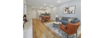 A living room with a grey couch and a wooden floor.