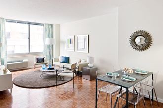 a living room with a dining table and a couch in front of a window
