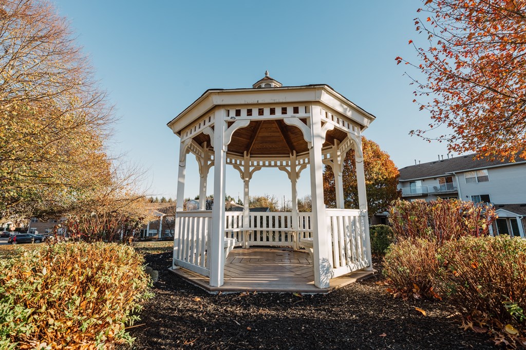 a white gazebo with a wooden deck in a yard