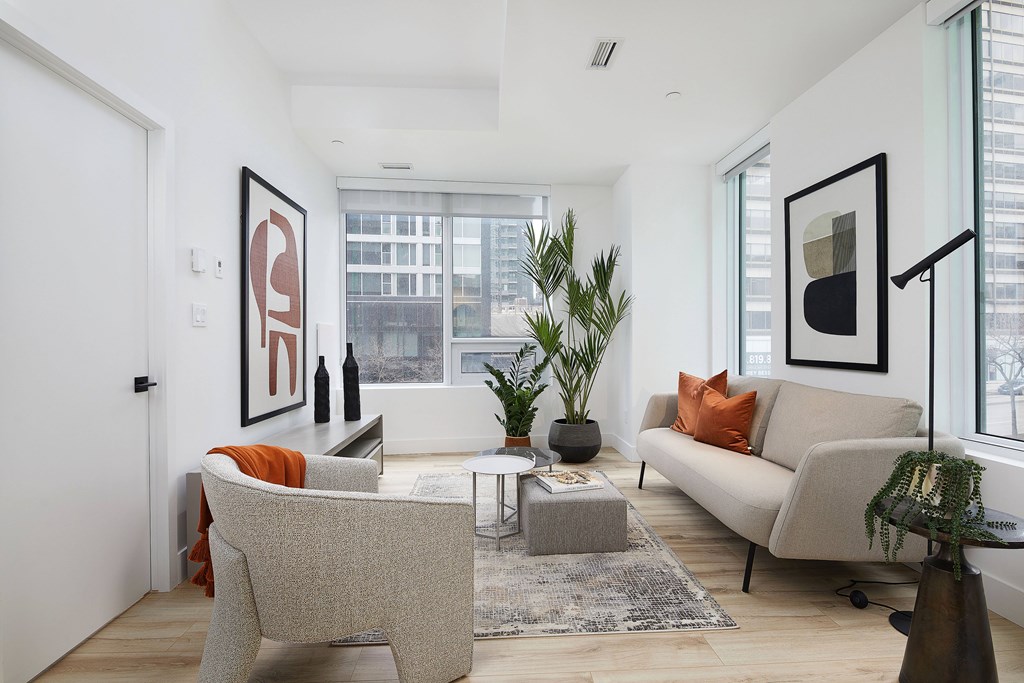 A living room with a grey couch, a grey chair, a coffee table, and a large window.