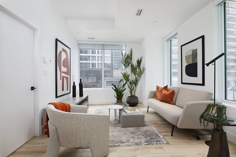 A living room with a grey couch, a grey armchair, a coffee table, and a large window.