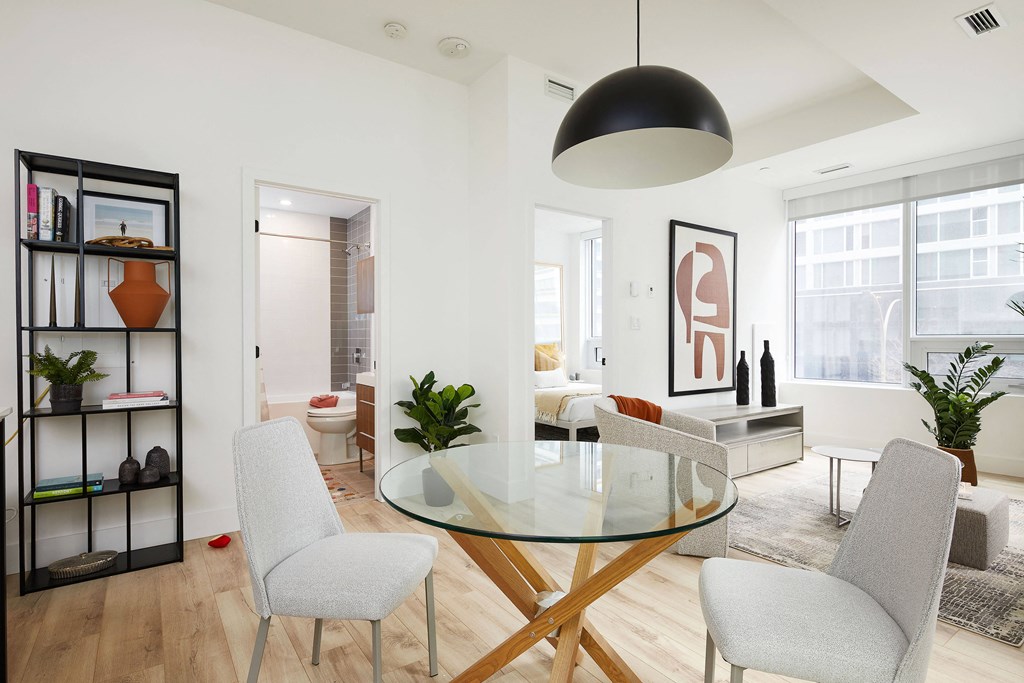 A modern dining room with a glass table and grey chairs.