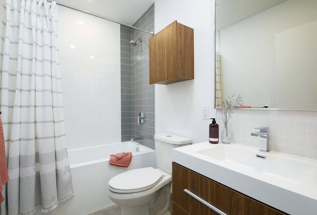 A white bathroom with a toilet, sink, and shower.