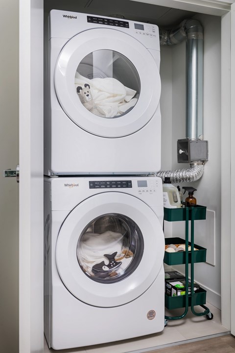 Two Whirlpool washing machines stacked on top of each other in a laundry room.