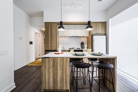 a kitchen with a center island and stools in a 555 waverly unit