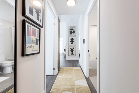 A hallway with a rug and pictures on the wall.