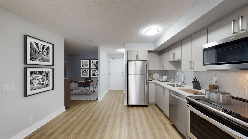 an open kitchen and living room with a stainless steel refrigerator