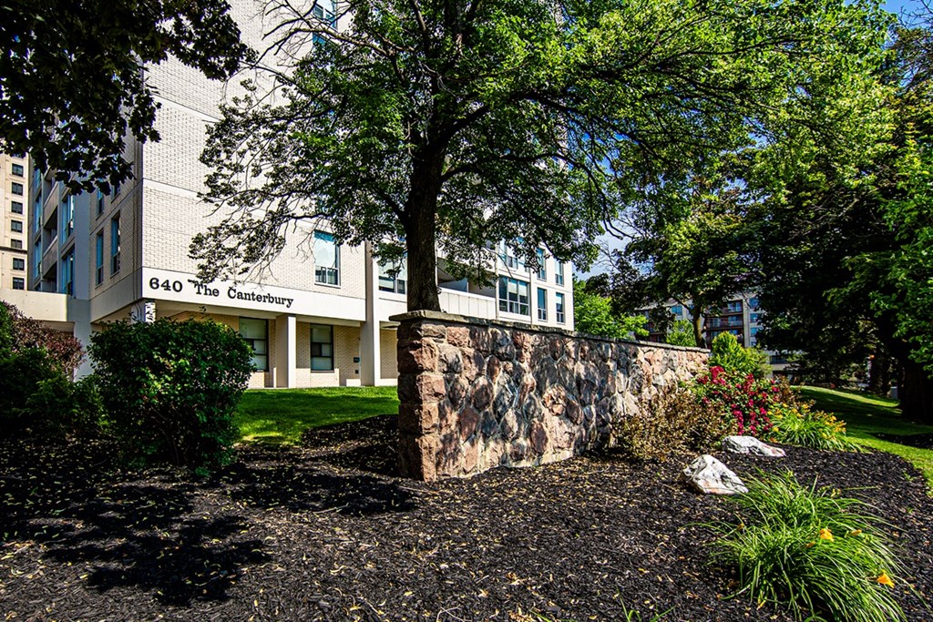 a stone wall with a tree in front of a building