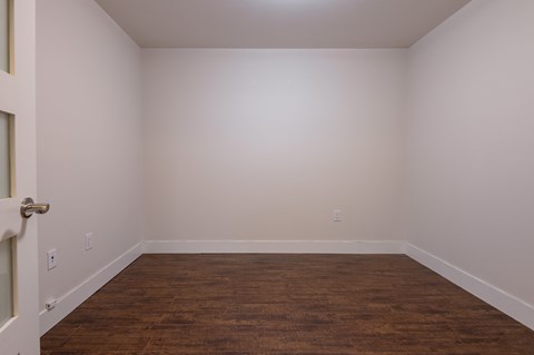 an empty room with a wood floor and white walls