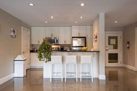 a modern kitchen with white cabinets and a bar with white stools
