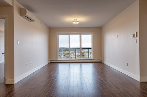 an empty living room with wood floors and a large window