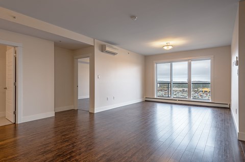 an empty living room with wood floors and a large window