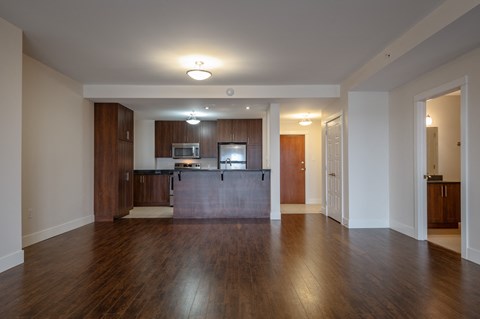 an empty living room and kitchen with wood flooring and