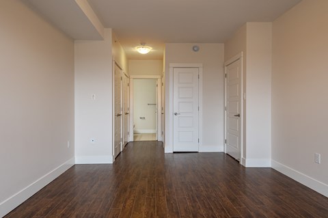 an empty living room with wood floors and white walls