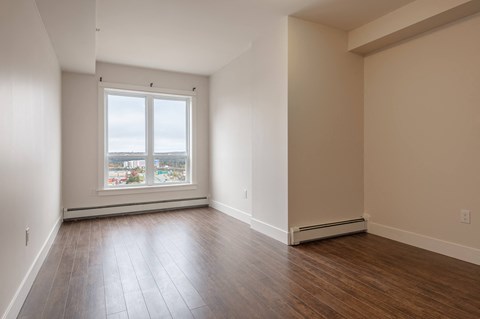 an empty living room with wood floors and a window
