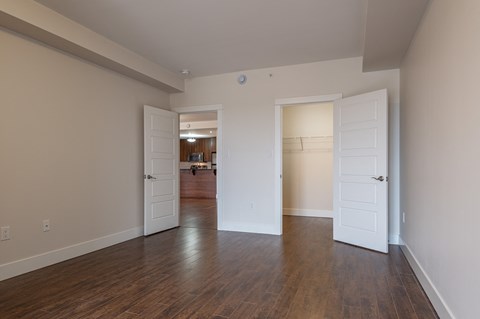 an empty living room with wooden floors and white doors