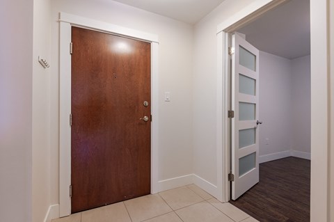 an empty room with a wooden door and a hallway with a white wall and a