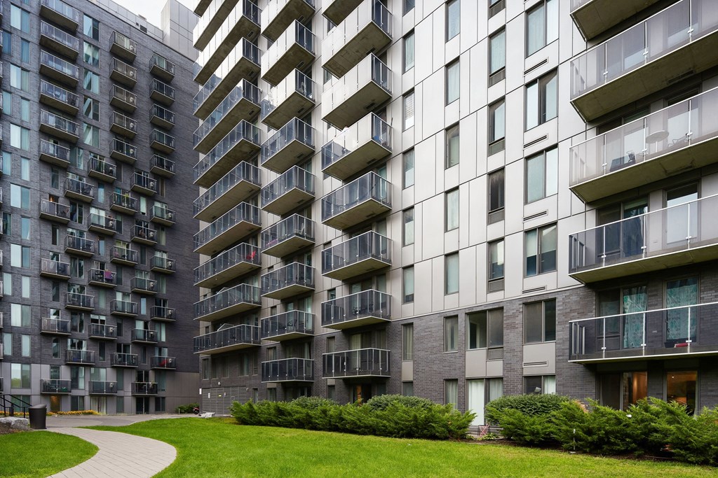 a large apartment building with many balconies and a green lawn