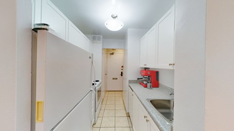A kitchen with white cabinets and a red appliance.