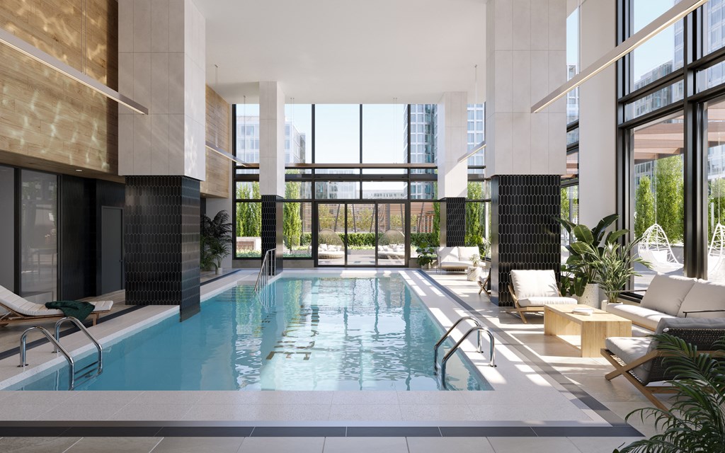 A large indoor swimming pool with lounge chairs and plants.