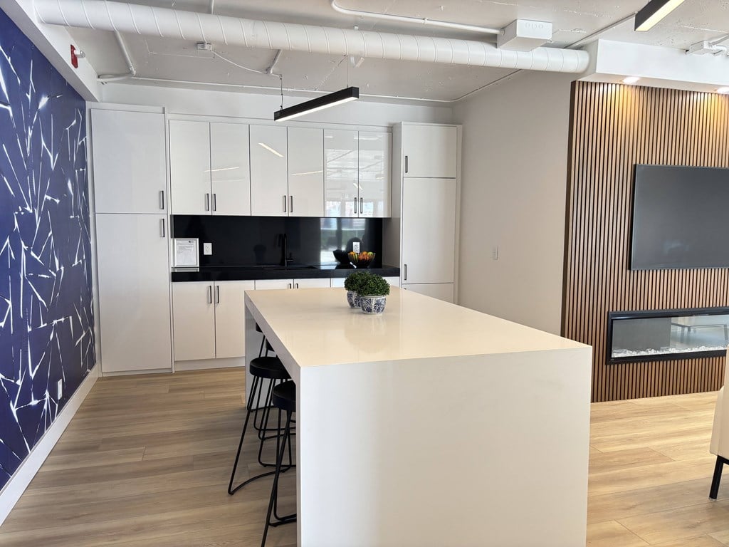 A modern kitchen with a white countertop and black bar stools.