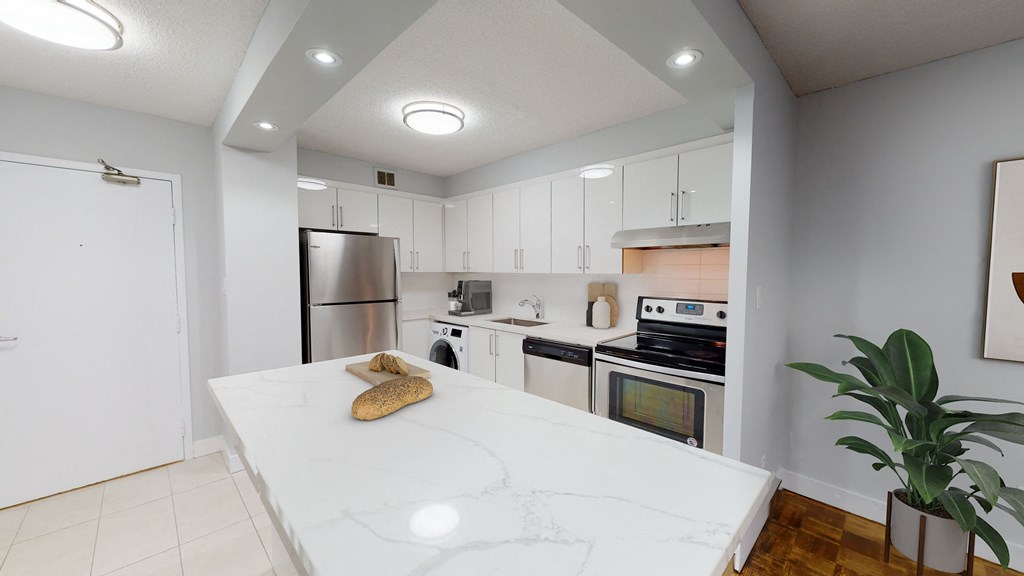 a large white kitchen with stainless steel appliances and a white counter top