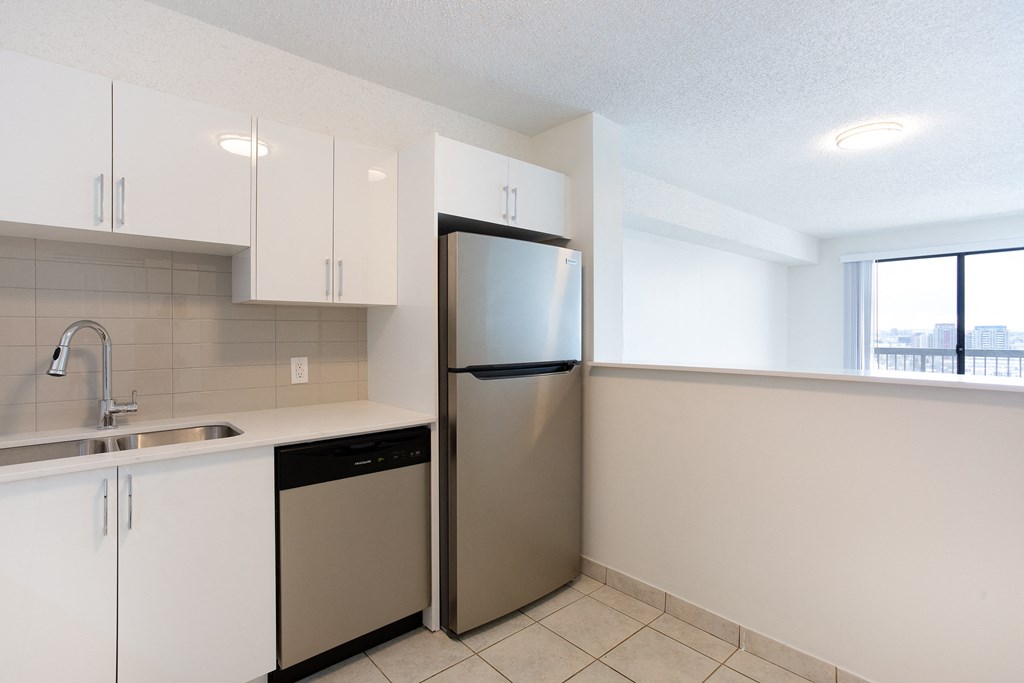 A kitchen with white cabinets and a stainless steel refrigerator.