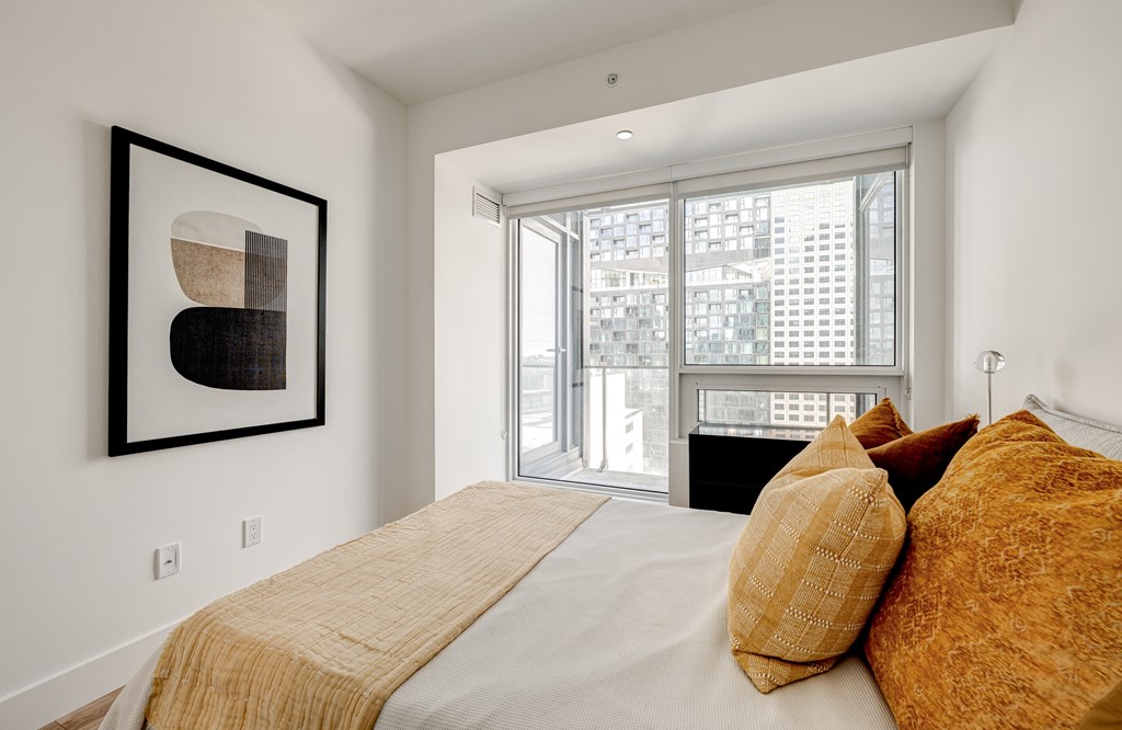 A bedroom with a large bed and a framed picture on the wall.