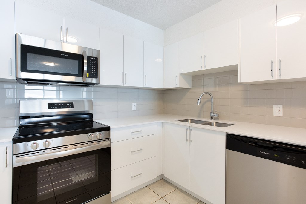 A modern kitchen with white cabinets and black appliances.