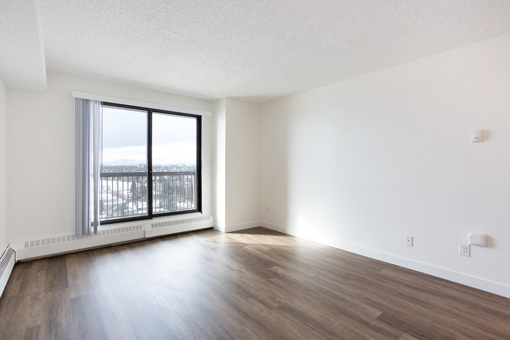 A room with a large window and wooden flooring.