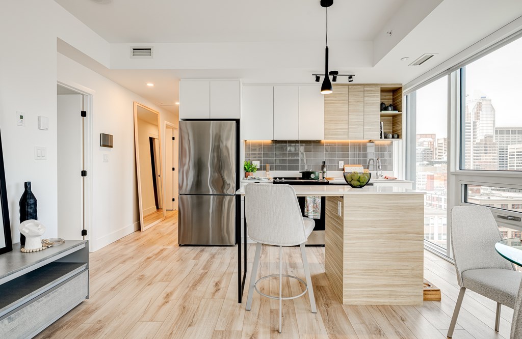 A modern kitchen with a wooden floor and a stainless steel refrigerator.