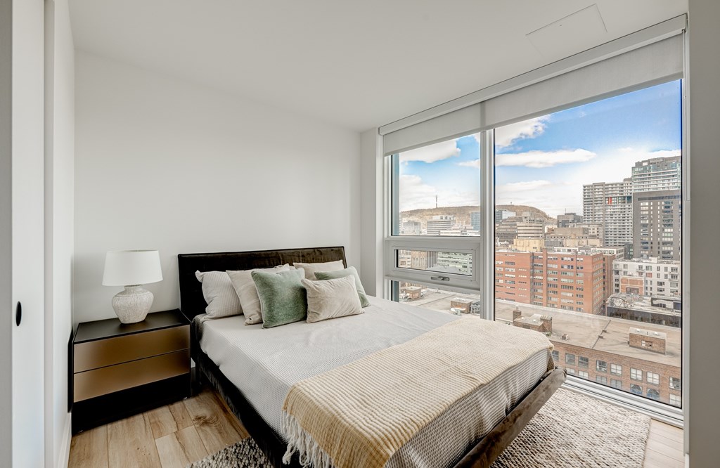 A bedroom with a large bed and a view of the city.