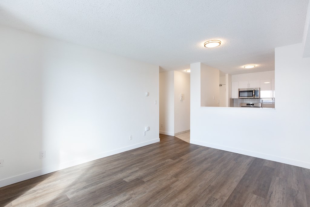 A spacious room with wooden flooring and white walls.