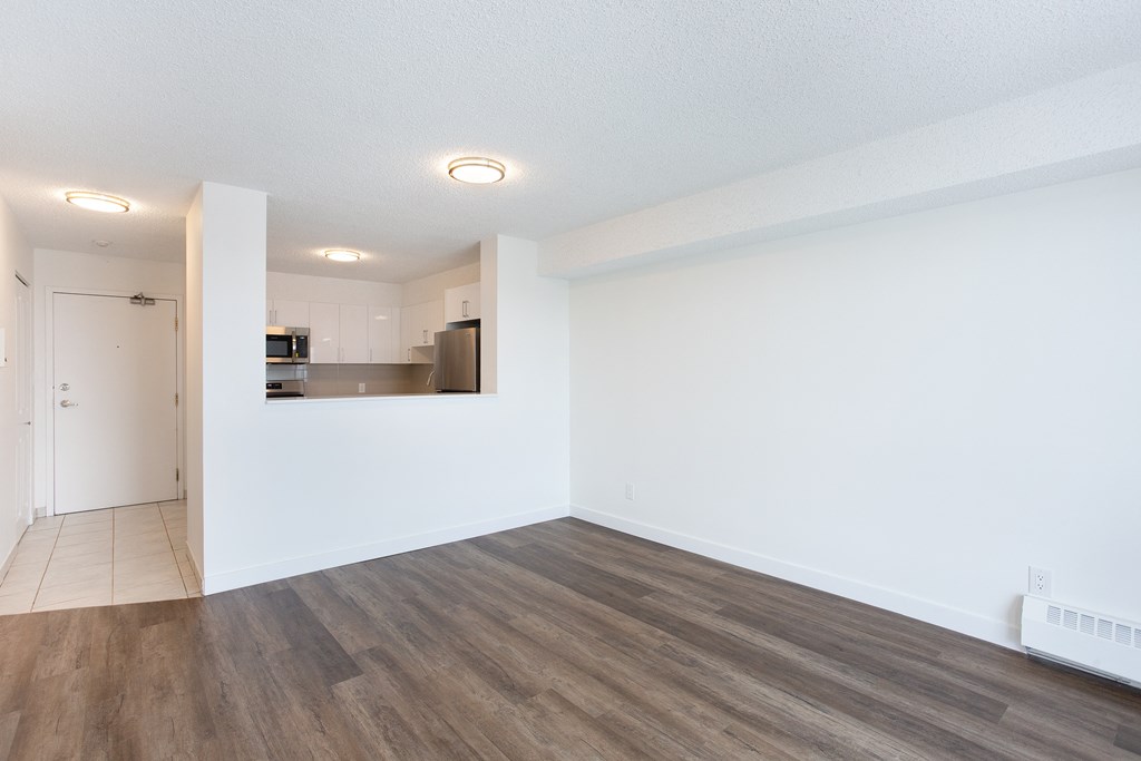 A room with a white wall and wooden flooring.