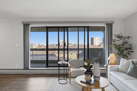 A modern living room with a view of the cityscape outside the large window.
