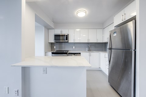 A modern kitchen with a stainless steel refrigerator and white cabinets.