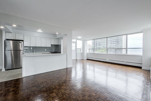 A spacious kitchen with a wooden floor and white walls.